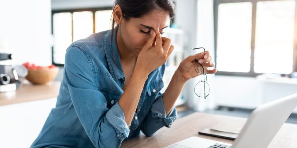 Shot of stressed business woman working from home on laptop looking worried, tired and overwhelmed.