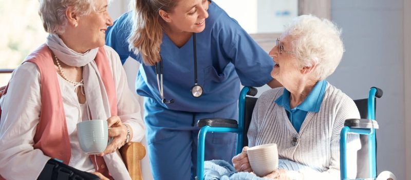 Nursing home, care and nurse with senior women doing healthcare checkup, examination or consultation. Medical, conversation and elderly woman in wheelchair consulting a doctor at retirement facility