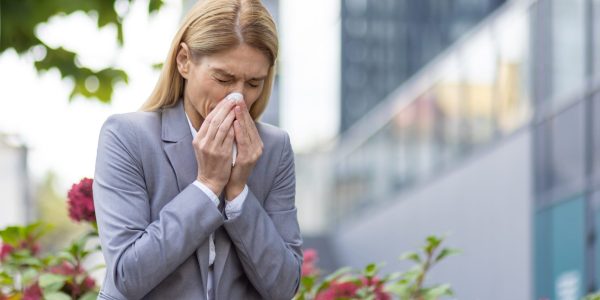 Businesswoman,Sneezing,Outdoors,Surrounded,By,Plants,,Possibly,Due,To,Allergies